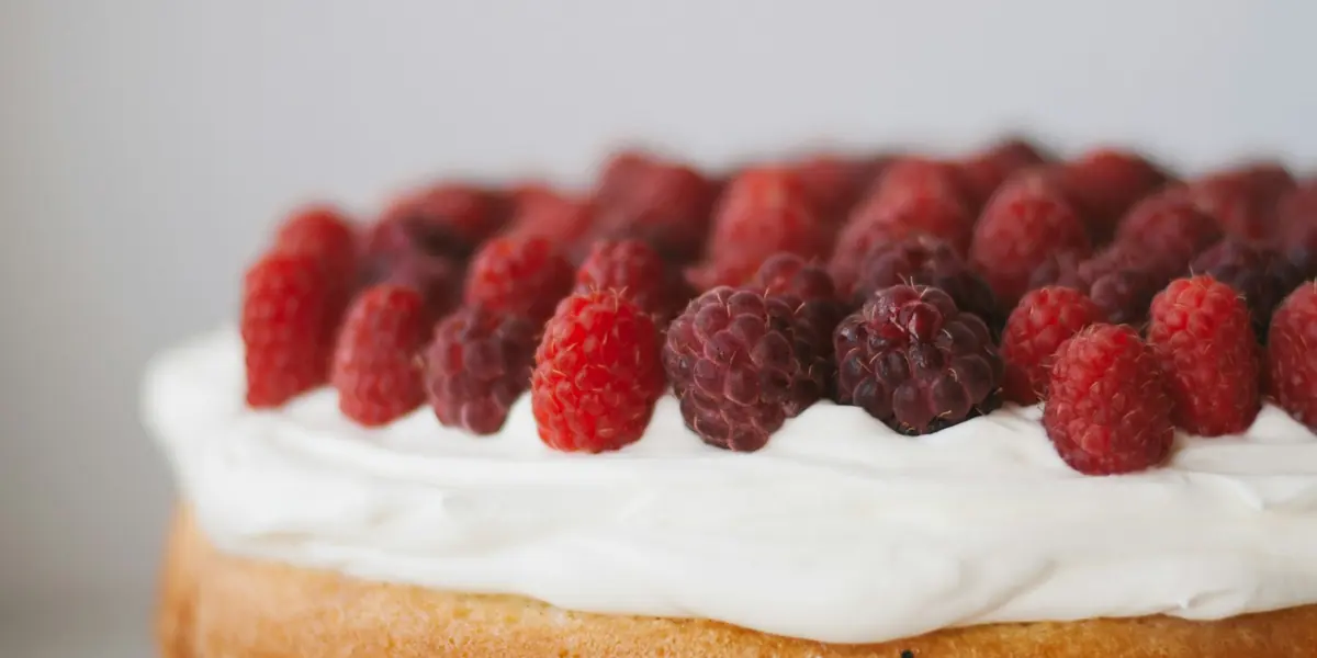Detalle de tarta con nata y frambuesas frescas